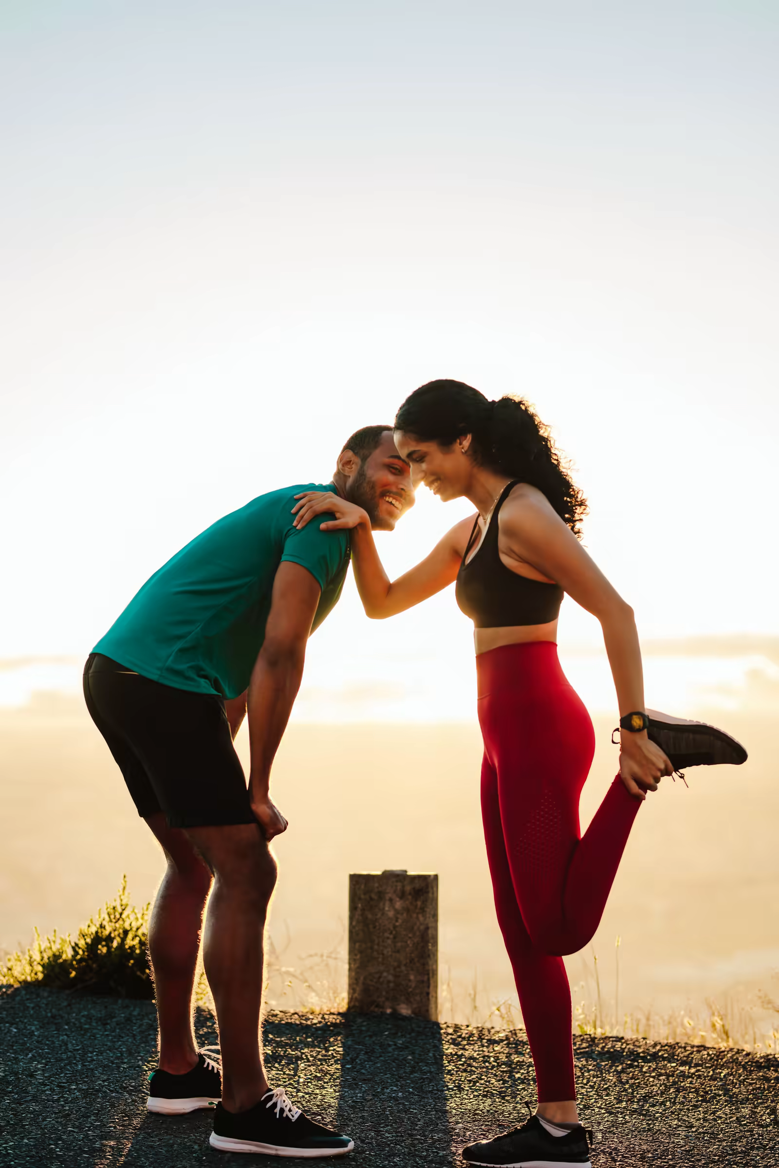 Couple stretching and touching foreheads on a hilltop at sunrise