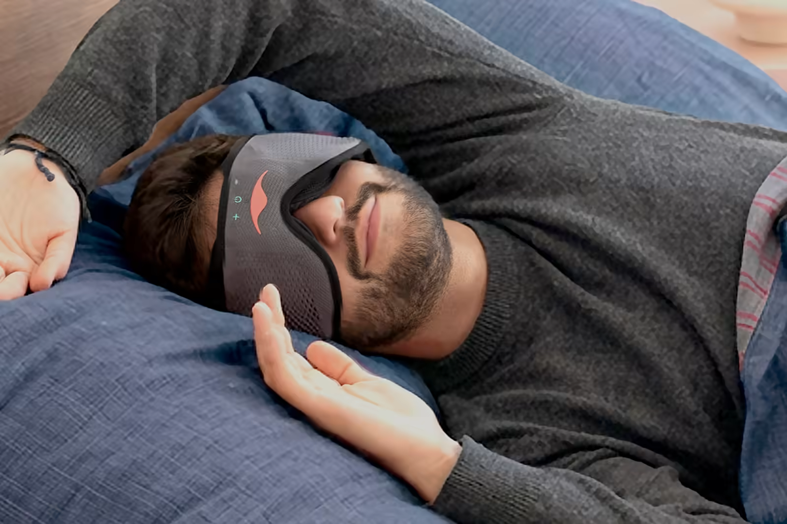 Man asleep on his side on a blue pillow in a Manta Sound sleep mask